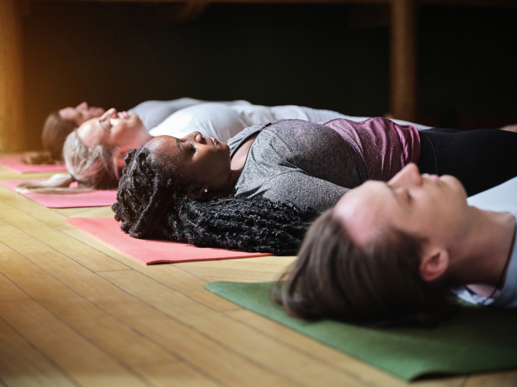 people laying down on yoga mats with eyes closed in relaxation