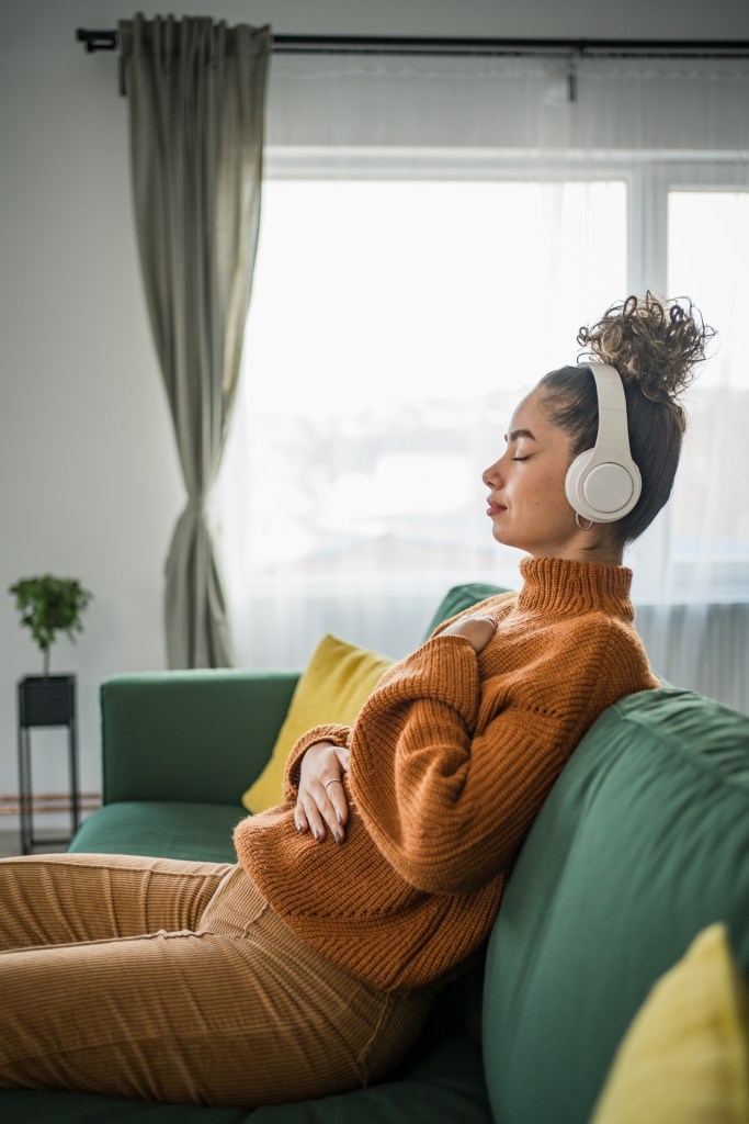 image of person with headphones, hands on heart, eyes closed