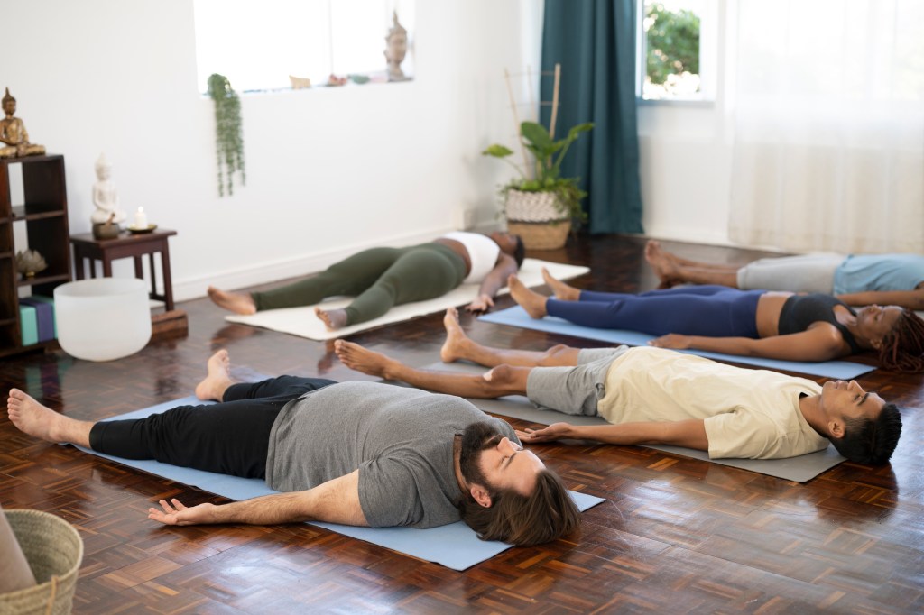 image of a group of people laying down on yoga mats in relaxation