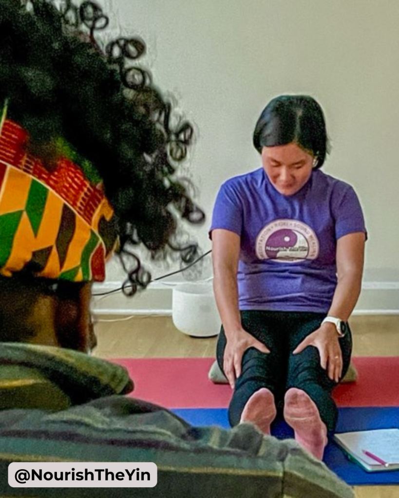 Image of Dorothy facilitating a movement class in a seated forward fold position.